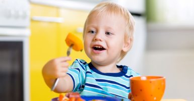 niño autónomo comiendo solo con un tenedor