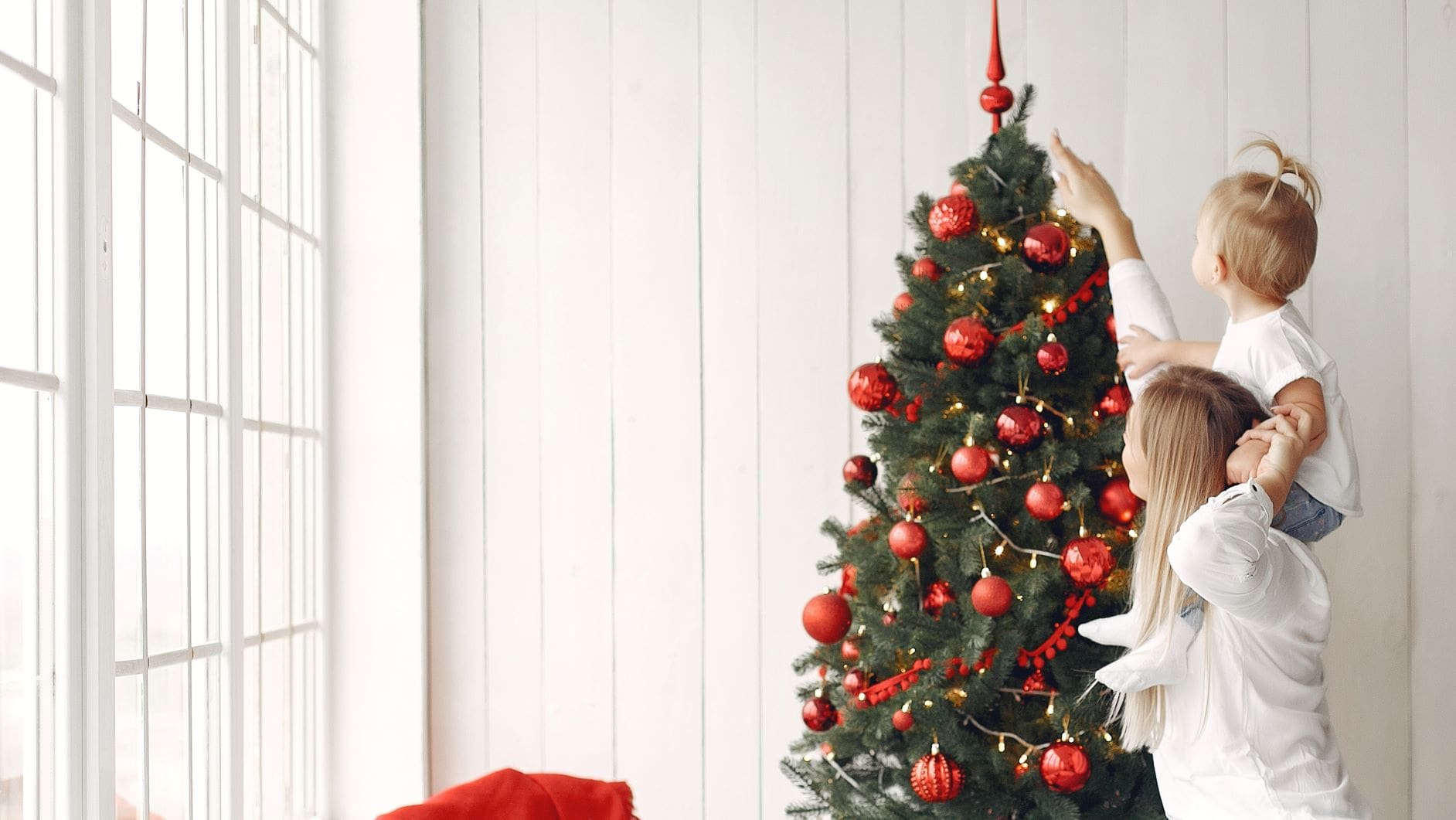mujer decorando el árbol de Navidad con su hijo